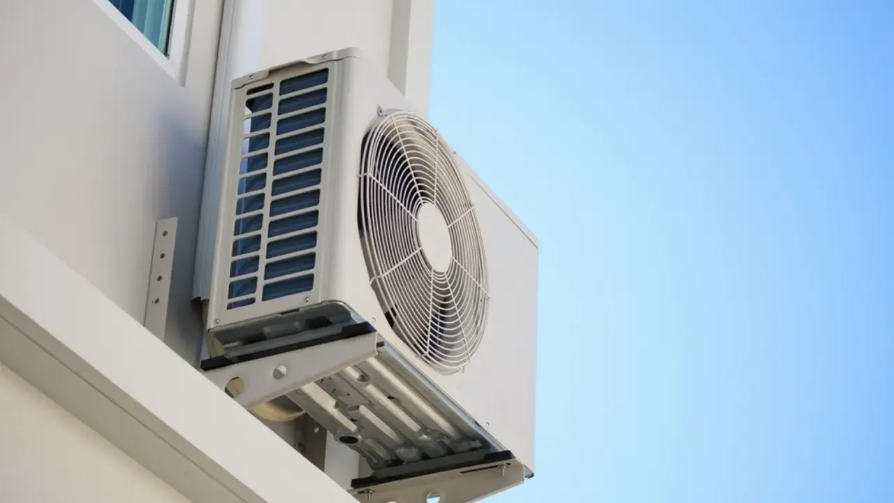 Unidad exterior de aire acondicionado montada en la pared de una terraza cerrada, lista para refrescar el ambiente.