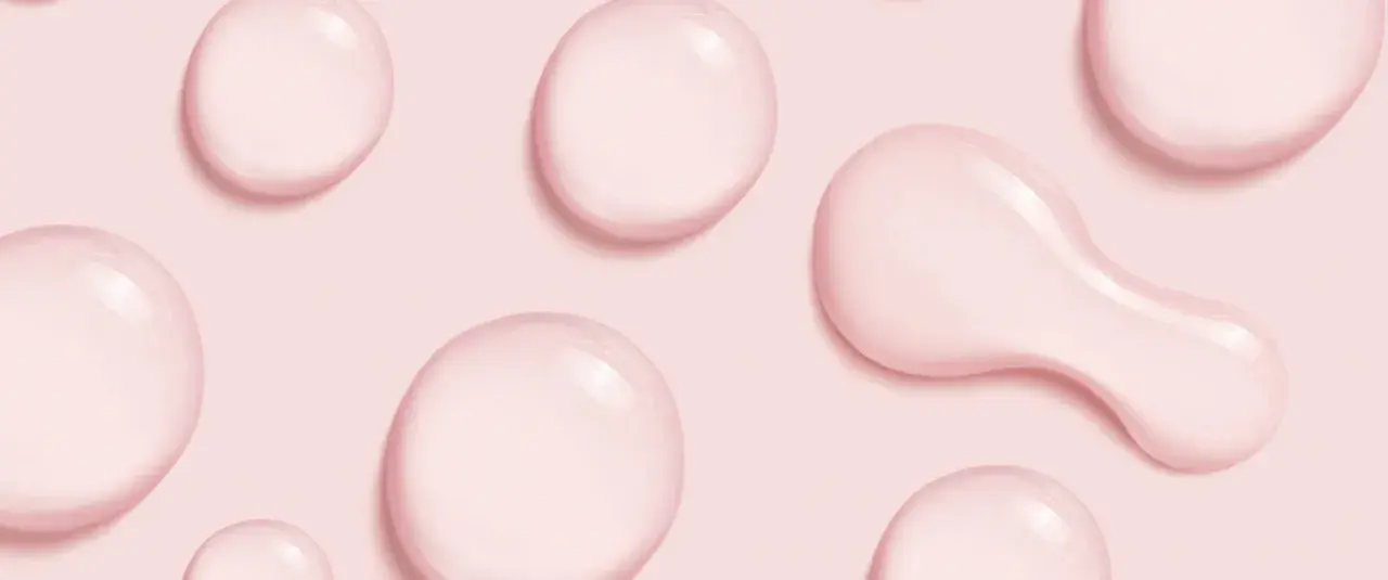 Gocce rosa su sfondo rosa, simili a quelle che si trovano in prodotti con cetearyl alcohol cos'è, un ingrediente emolliente.