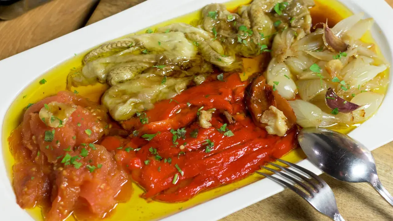 Deliciosa escalivada al forn con pimientos rojos, berenjenas, tomates y cebollas asadas, regada con aceite de oliva y perejil picado.
