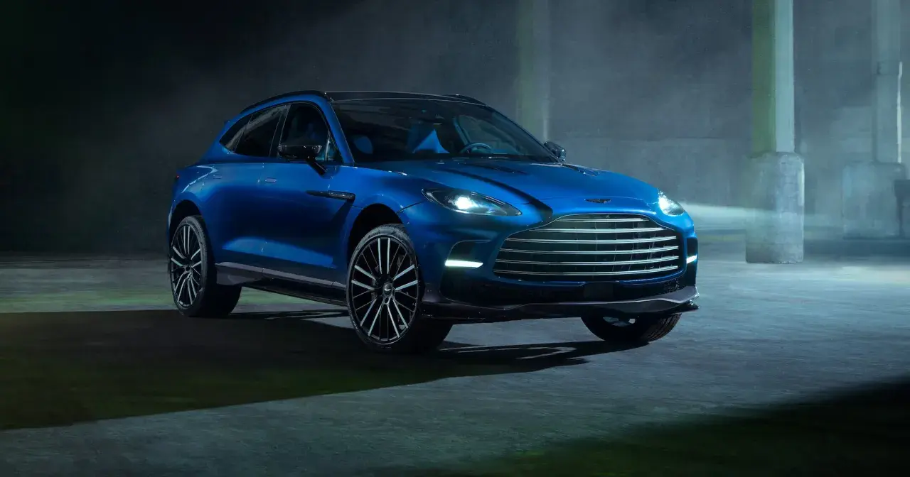 Niebieski Aston Martin DBX 707 lśni w mrocznym, industrialnym otoczeniu.