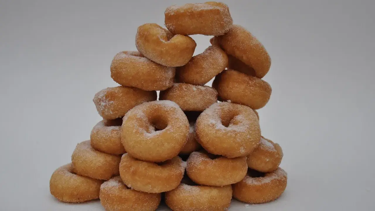 Pile de donuts dorés saupoudrés de sucre, parfaits pour une recette facile de donuts maison.