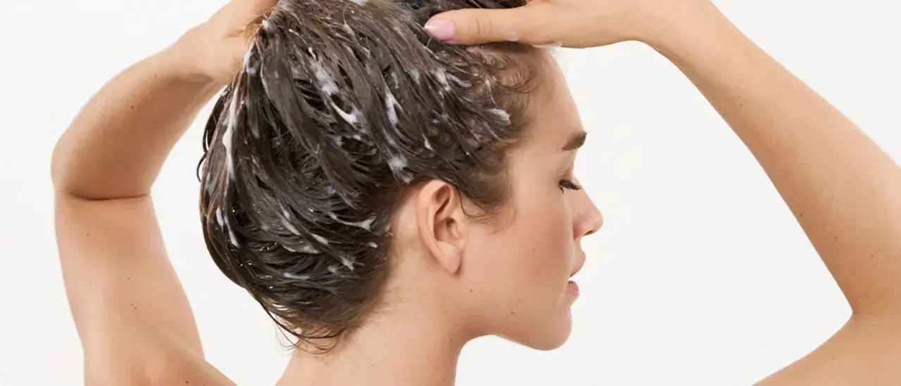 Frau wäscht sich die Haare, Schaum im Haar deutet auf die pflegende panthenol wirkung hin.