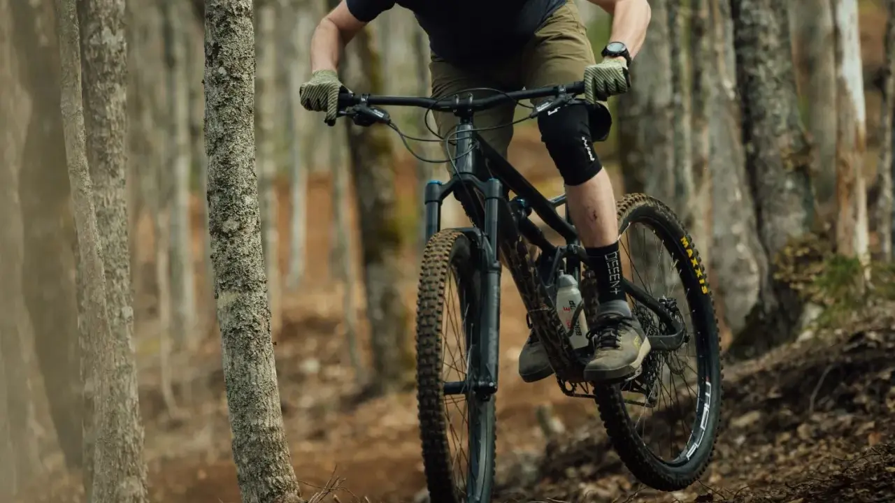 Rowerzysta w kasku i ochraniaczach pokonuje leśny szlak na rowerze górskim, jednym z wielu rodzajów rowerów do jazdy terenowej.