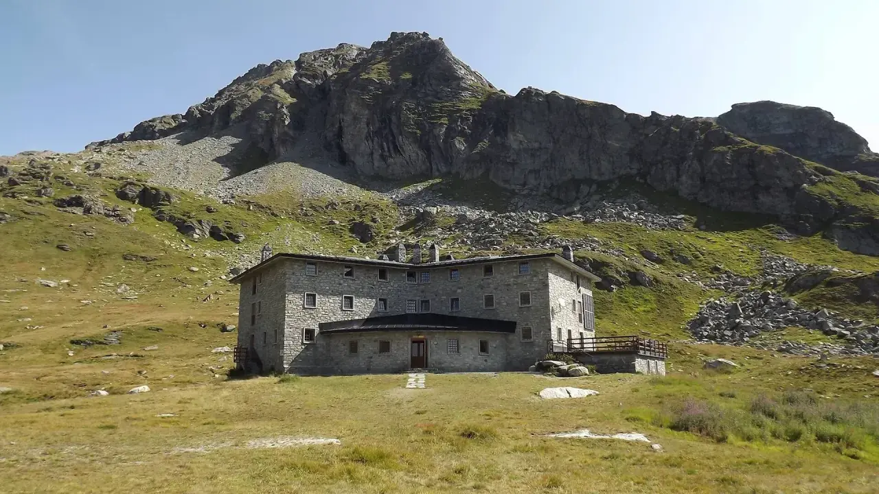 Un imponente rifugio in pietra, incastonato tra prati verdi e rocce imponenti, domina il paesaggio alpino. Un luogo ideale per chi cerca avventura e tranquillità nel cuore della Valle d'Aosta.