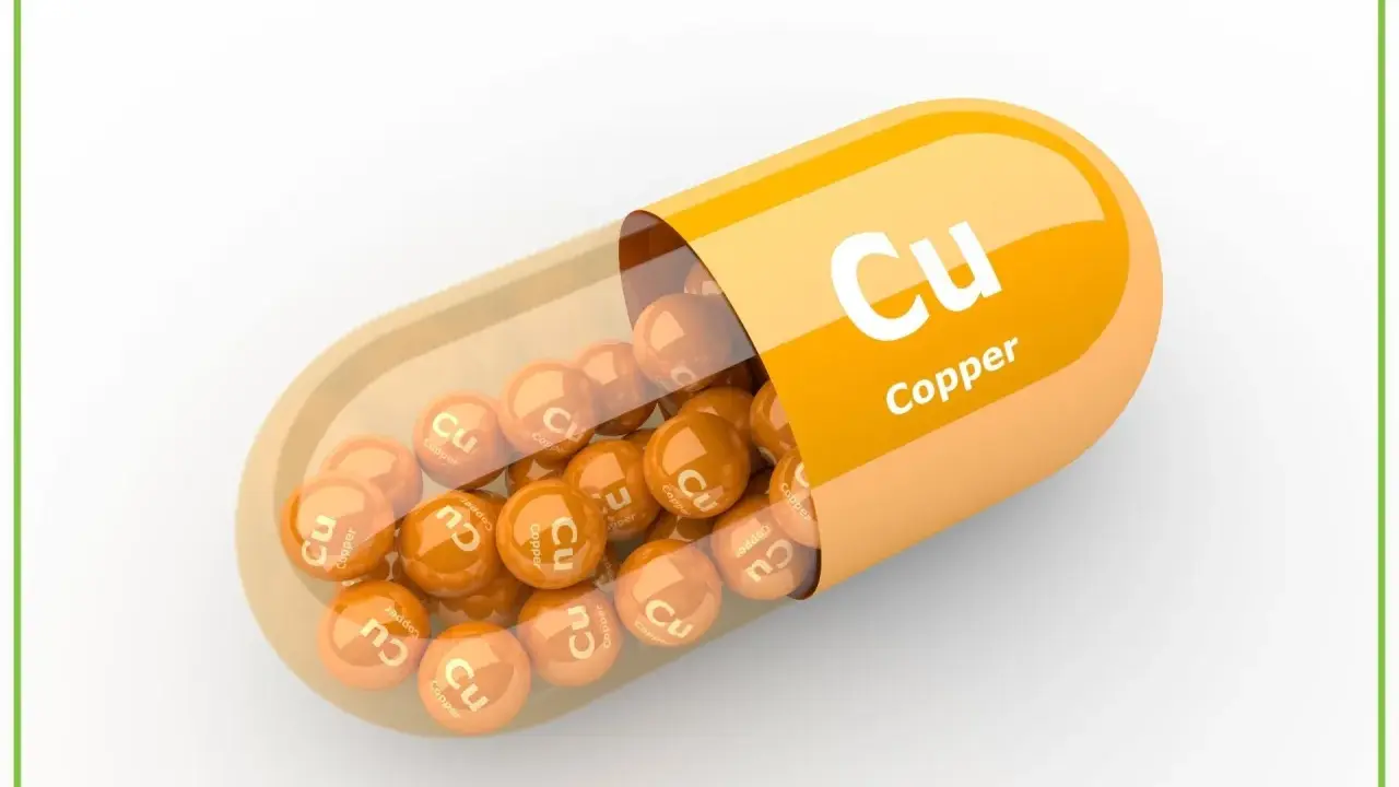 Pomarańczowa kapsułka z wysypującymi się z niej kulkami z napisem "Cu Copper". Suplement diety.