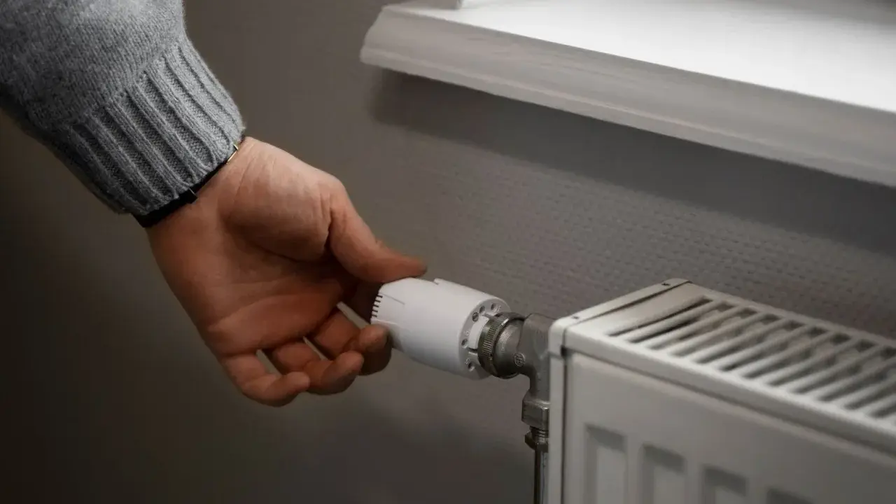Dłoń reguluje termostat grzejnika. To przykład histerezy, czyli opóźnienia reakcji systemu na zmianę.