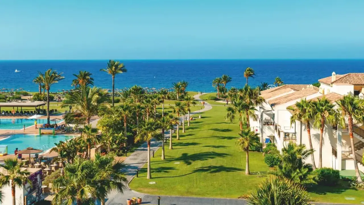 Traumhafter Blick auf das Granada Meer, Palmen säumen den Weg zum Pool und den weißen Hotelgebäuden.