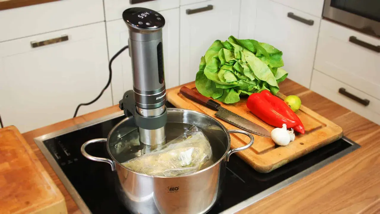 Sous vide garen: Ein Stab im Wasserbad, daneben frisches Gemüse auf einem Holzbrett. Perfekt für zarte Ergebnisse.