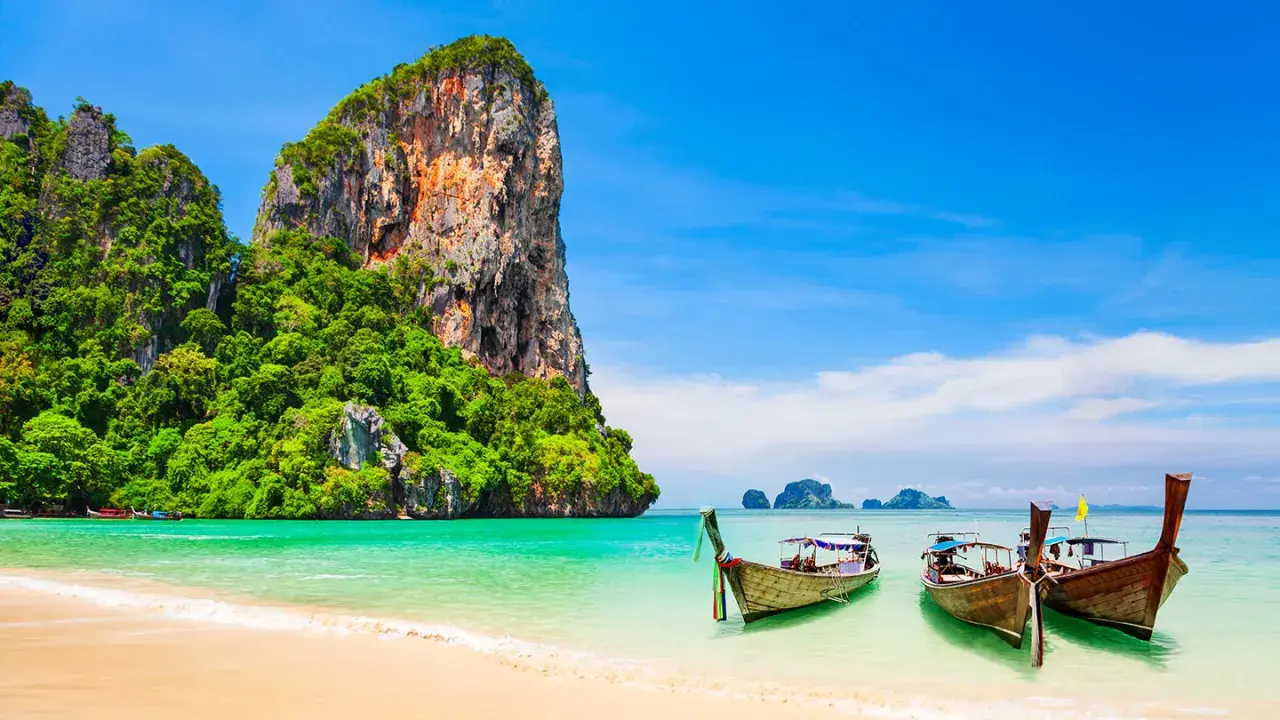 Klong Nin Beach med turkost vatten, vita stränder, grönskande klippor och traditionella longtailbåtar. En idyllisk thailändsk dröm.
