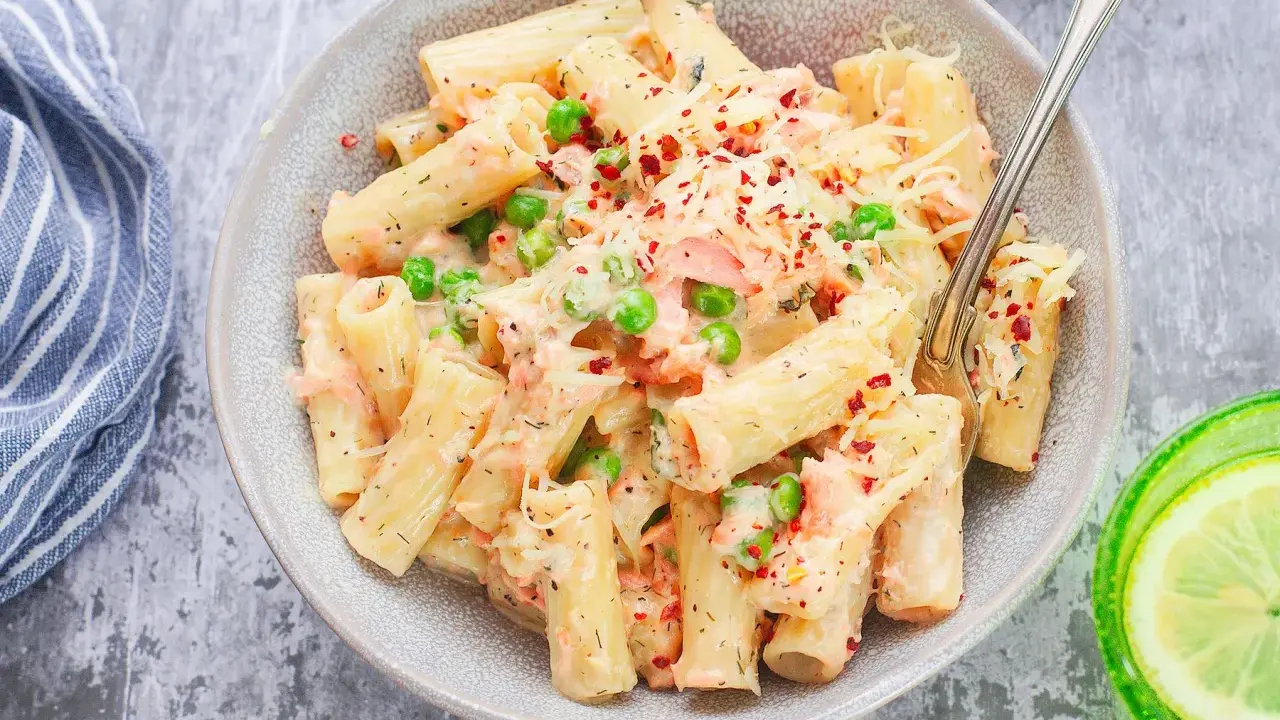 Pyszne danie z makaronem rigatoni, kawałkami łososia, groszkiem i kremowym sosem, posypane serem i płatkami chili. Idealna pasta z łososia na obiad.