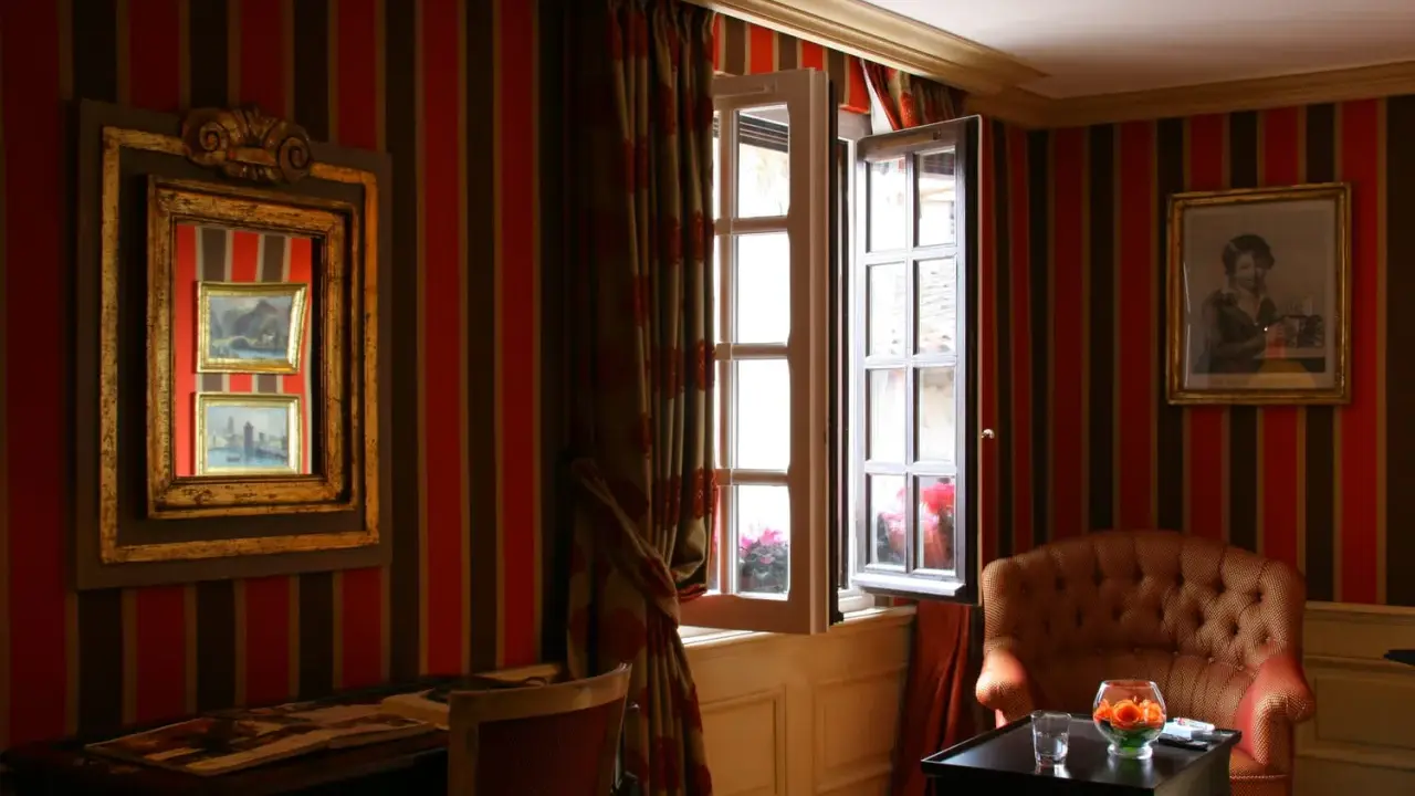 Fenêtre ouverte et miroir pour comment éclaircir une pièce sombre. Un fauteuil confortable et un bureau complètent ce décor.