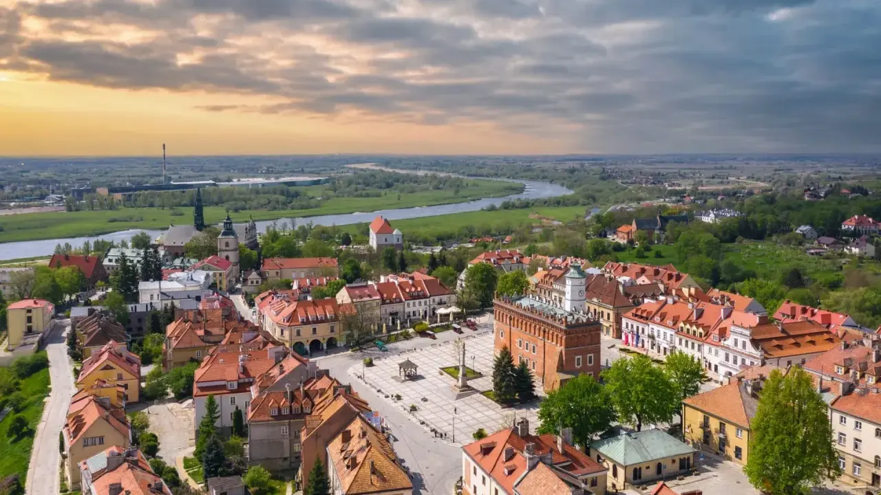 Urokliwy rynek i rzeka w miasto zakochanych w Polsce. Dachy kamienic i zieleń tworzą malowniczy krajobraz.