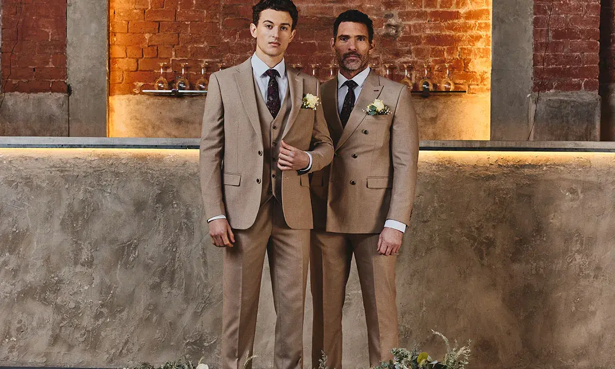 Two men in tan suits stand side-by-side. The man on the left wears a single-breasted suit, while the man on the right wears a double-breasted suit.