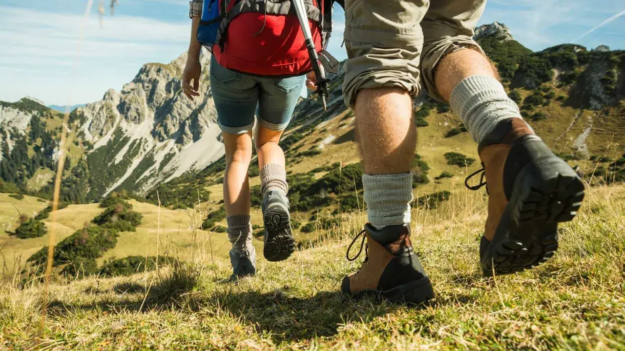 Dobre buty w góry latem to podstawa. Para wędrowców w solidnych trekkingowych butach i skarpetach pokonuje górski szlak.