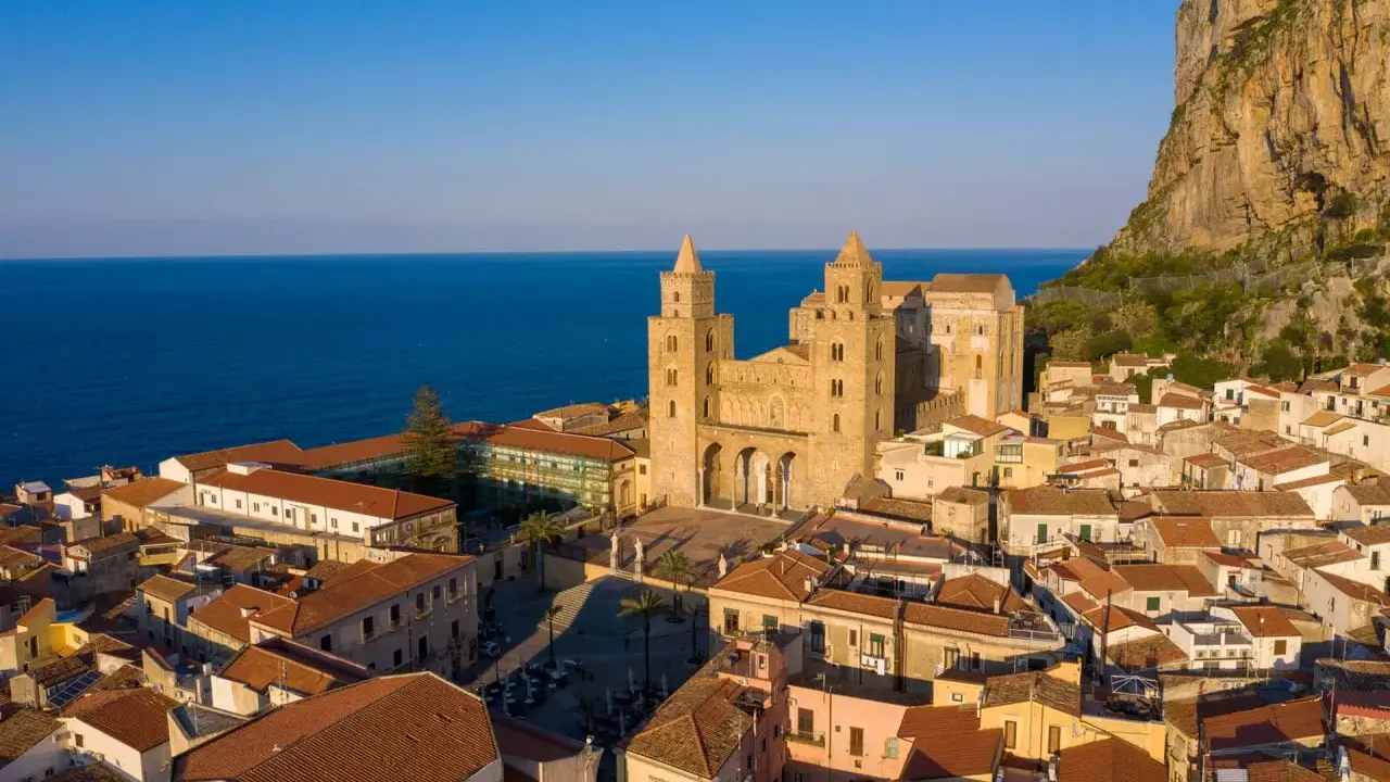 Cefalù cosa vedere: la maestosa Cattedrale Normanna domina il borgo con le sue torri, incastonata tra il mare blu e la rocca imponente.