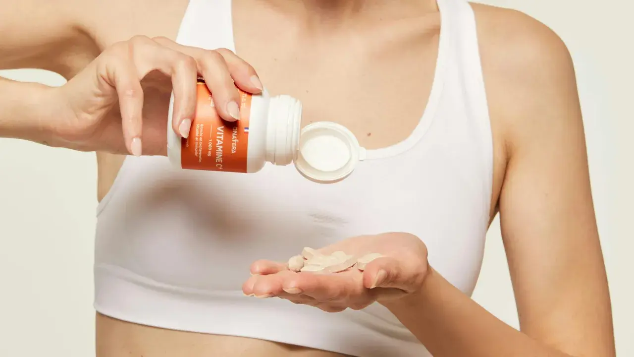 Une main verse des comprimés de vitamine C dans l'autre main, pour une cure revitalisante.