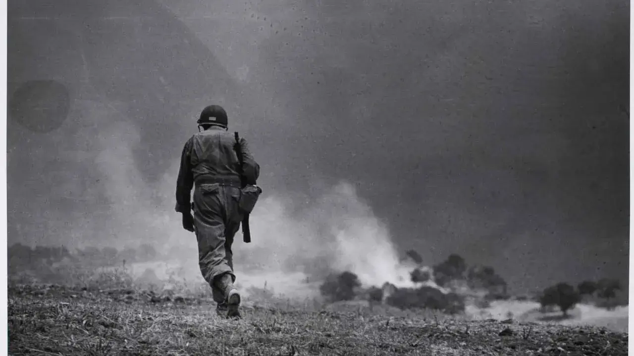 Soldato solitario cammina verso il fumo di battaglia, un'iconica immagine di Robert Capa.