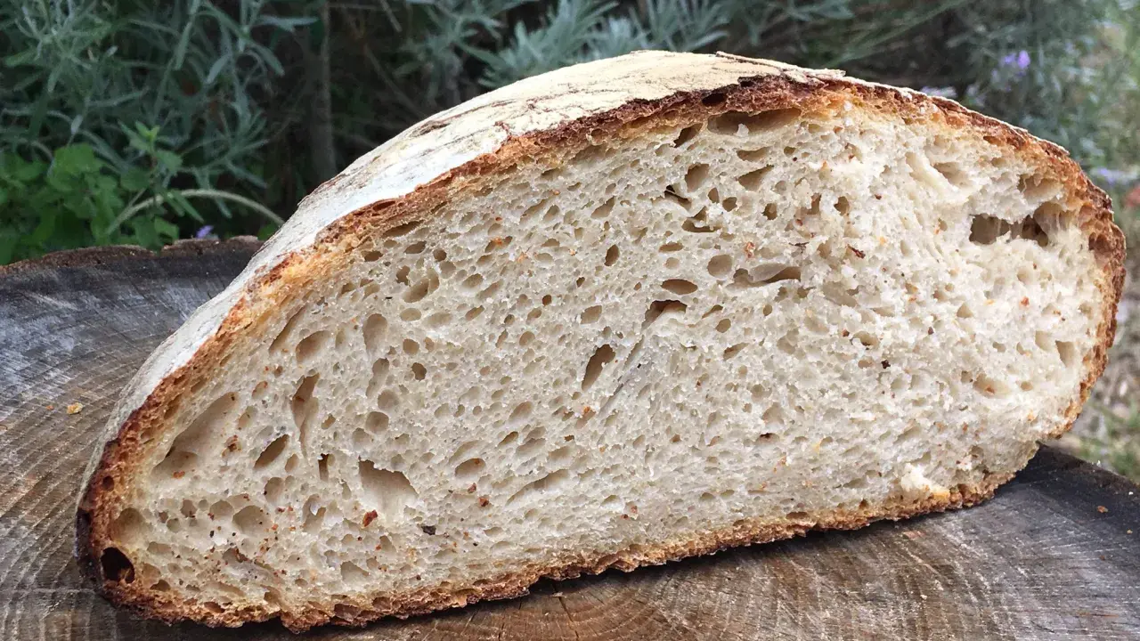 Une mie aérée et une croûte dorée pour ce pain au levain rapide, posé sur une tranche de bois.