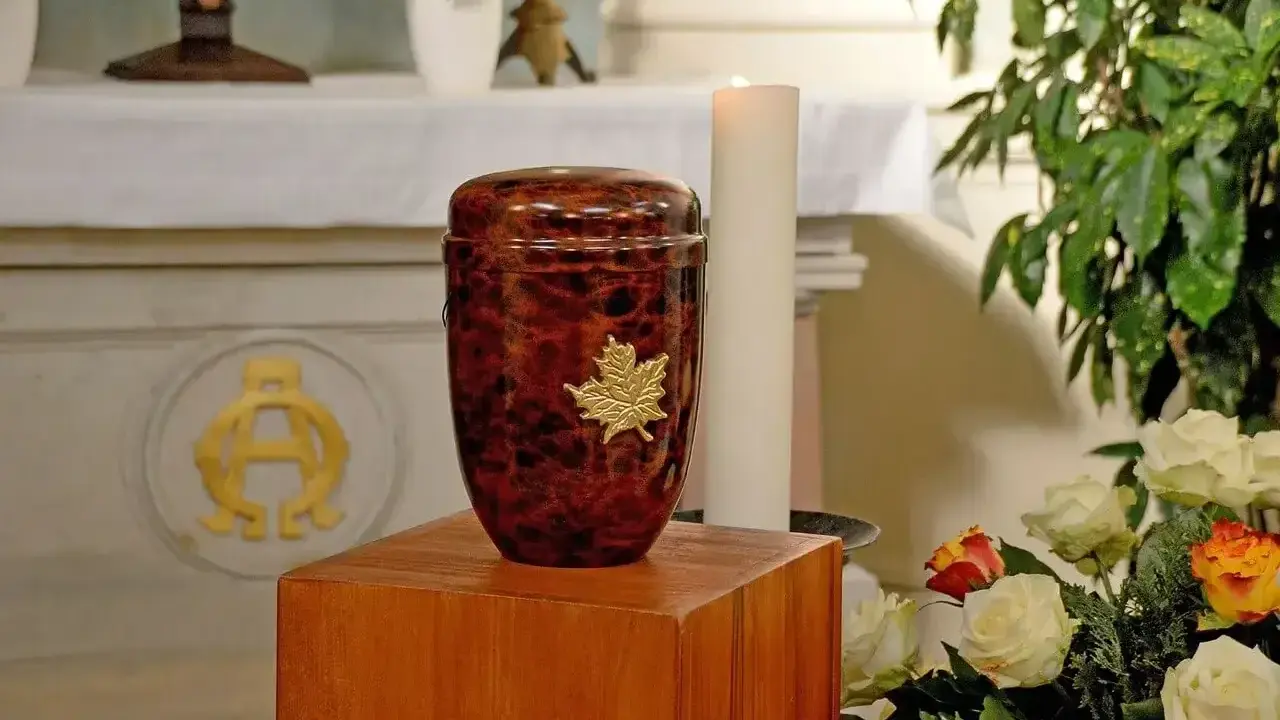 Elegancka, brązowa urna z liściem klonu, symbolizująca pamięć. To miejsce spoczynku prochów, co to urna.