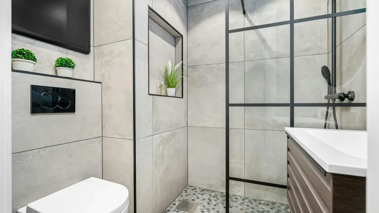Mampara de ducha con diseño de ventana, separando el espacio de la ducha. Baño moderno con inodoro y lavabo.