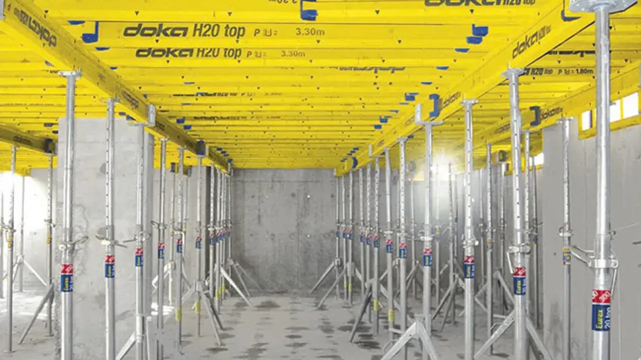 Sistema de apeo estructural Doka H20 top, con puntales metálicos y vigas amarillas, listo para soportar una losa.