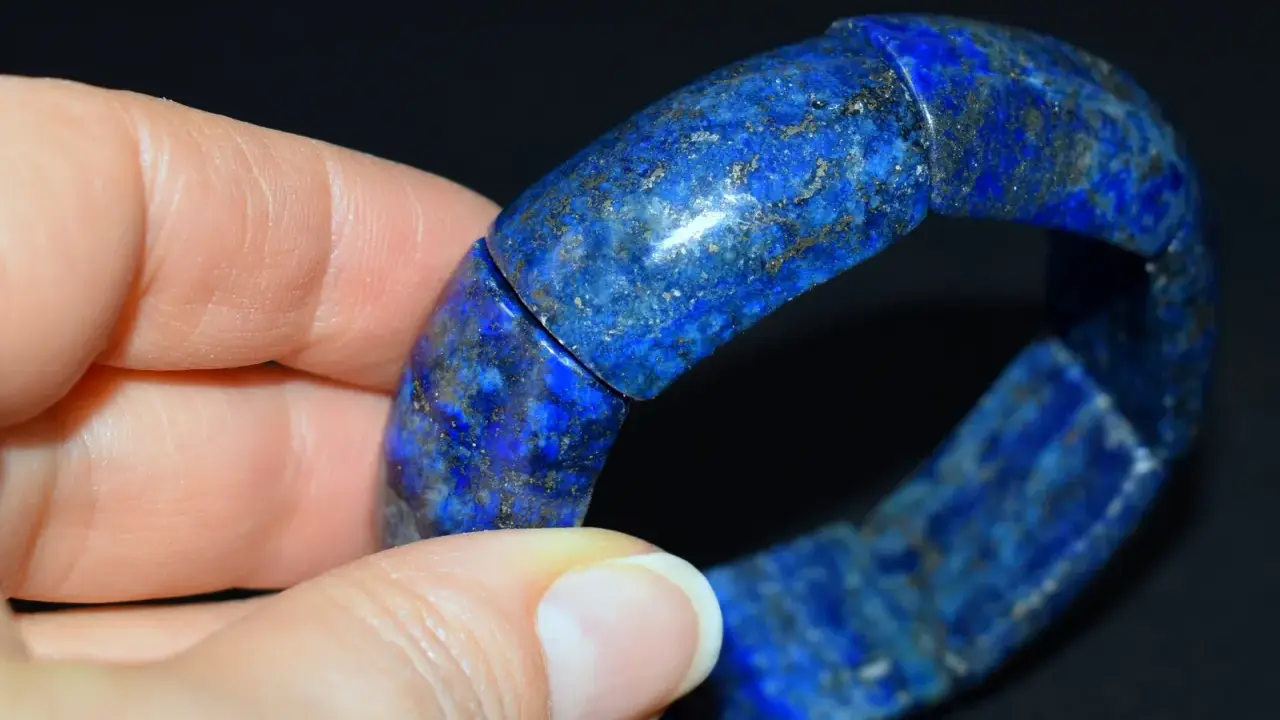 Błękitna bransoleta z lapis lazuli, z widocznymi złotymi inkluzjami pirytu, prezentowana na dłoni.