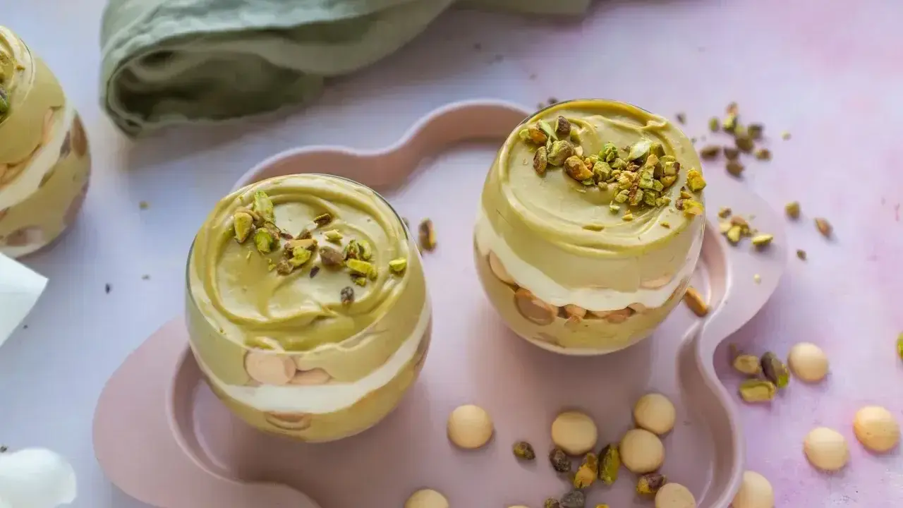 Dwa pucharki z kremem pistacjowym z mascarpone, udekorowane posiekanymi pistacjami.