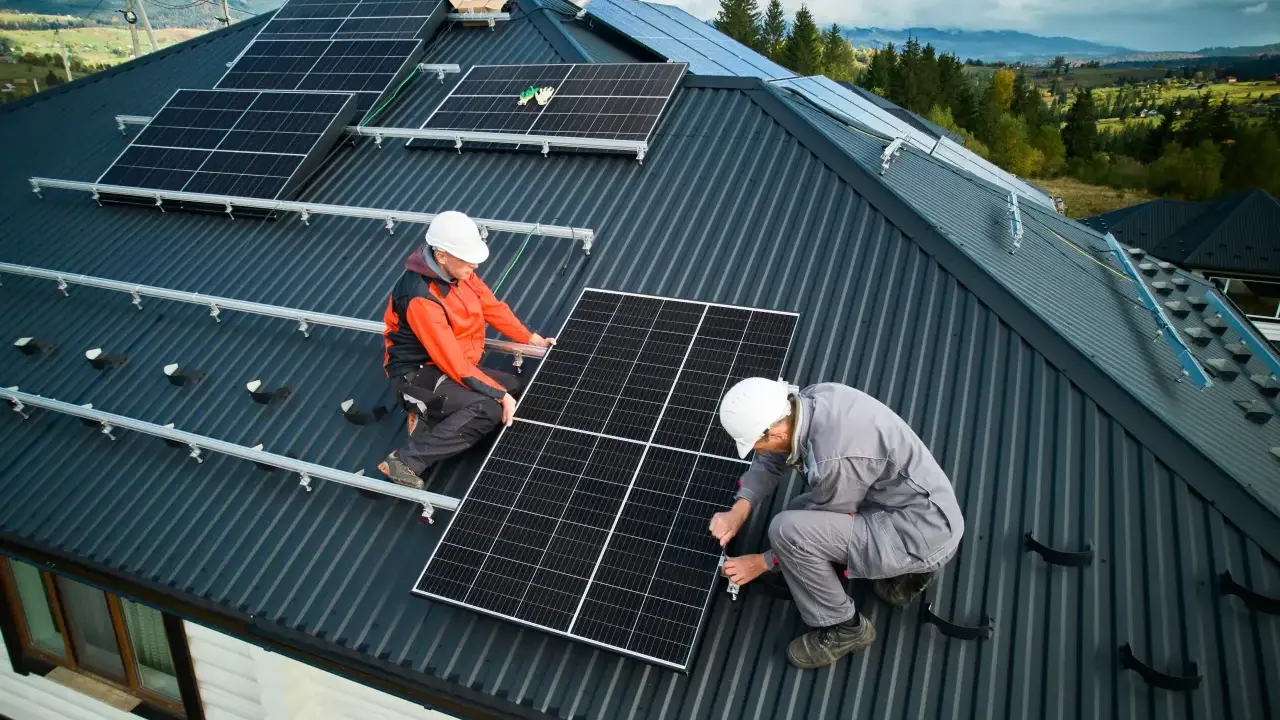 Zwei Monteure installieren Solarmodule auf einem Dach. Die Frage "was kostet eine PV Anlage mit Speicher" beschäftigt viele Hausbesitzer.