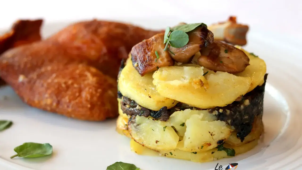Plat de pommes de terre en millefeuille avec du foie gras et des champignons, accompagné de volaille rôtie.