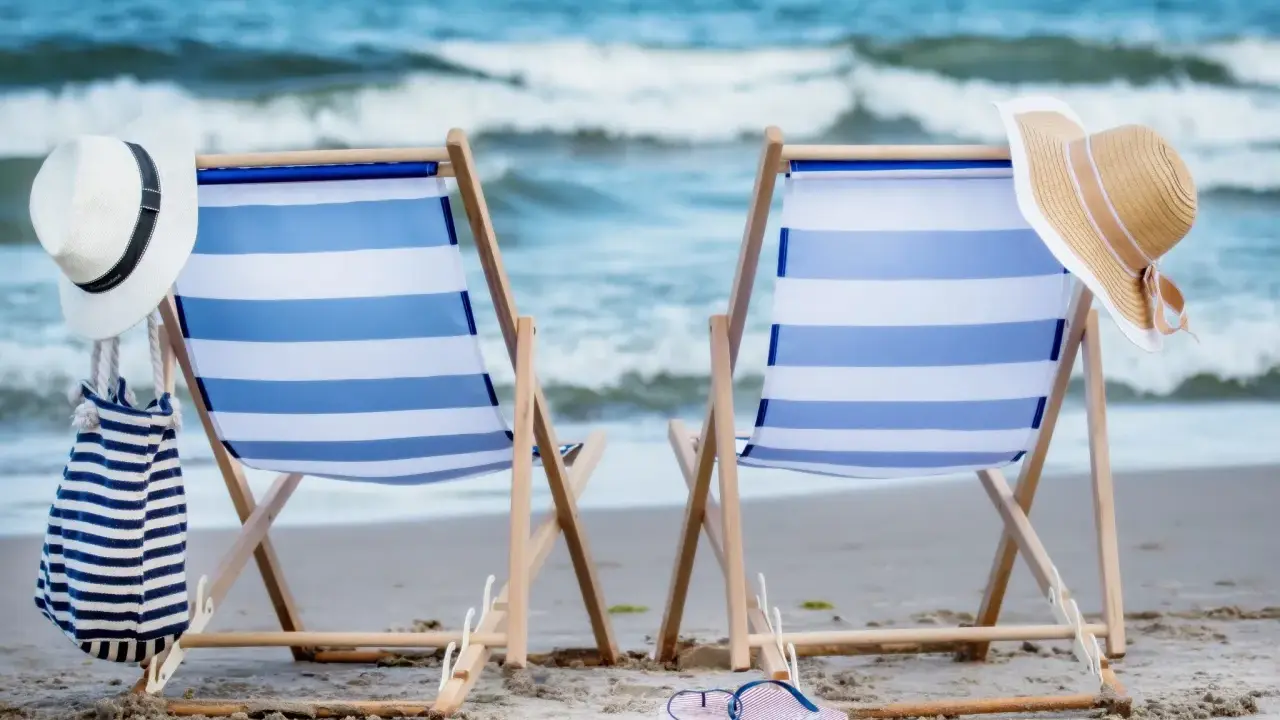 Dwa leżaki na plaży, gotowe na idealny weekend nad morzem. W tle szum fal i błękitne niebo.