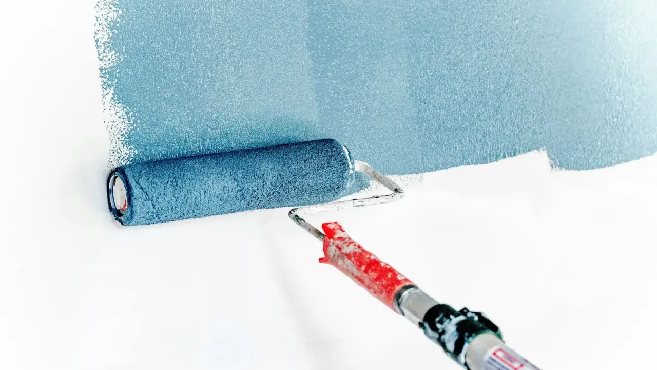 Rodillo aplicando pintura azul sobre pared blanca. La imprimación es el primer paso para un acabado perfecto.