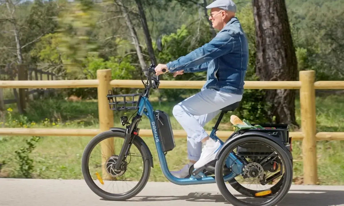 Un homme âgé roule sur un tricycle électrique bleu, son certificat d'homologation vélo électrique en poche.