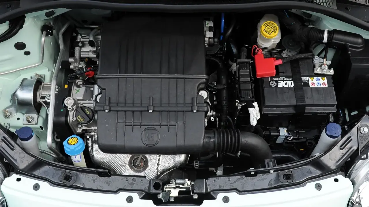 Silnik Fiata 500 L z widocznym logo FIAT na czarnej obudowie. Widać akumulator, płyny i elementy układu chłodzenia.