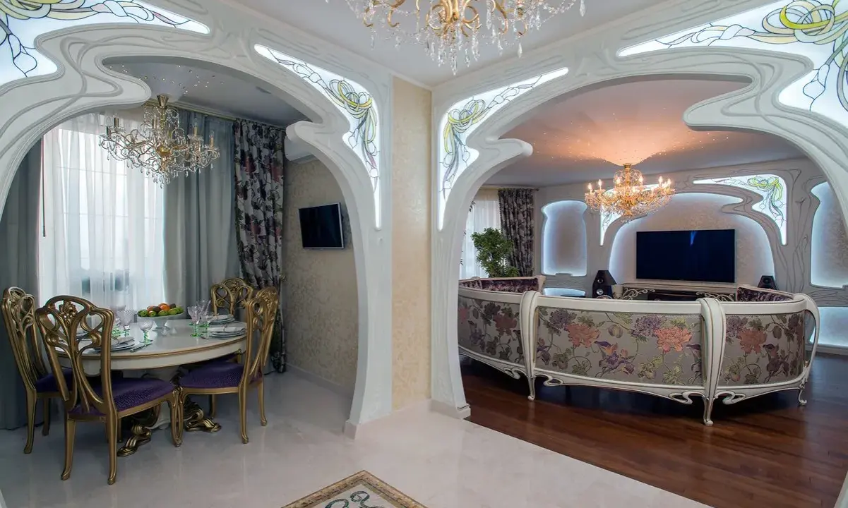 Ett lyxigt vardagsrum och matsal i art nouveau jugendstil med blommig soffa, kristallkronor och utsmyckade valv.