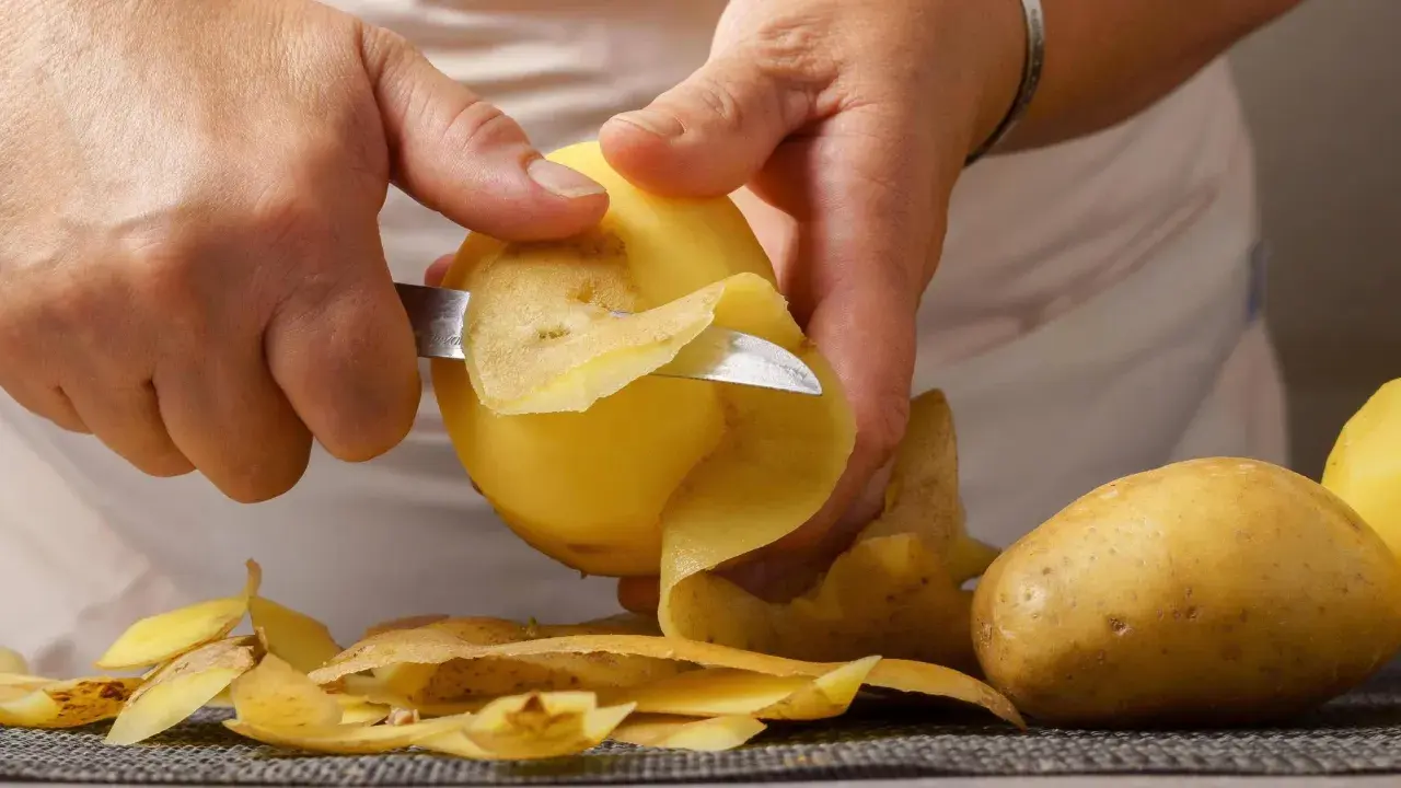 Hände schälen Kartoffeln für die Zubereitung. Bald sind die Kartoffeln gar und bereit zum Genuss.