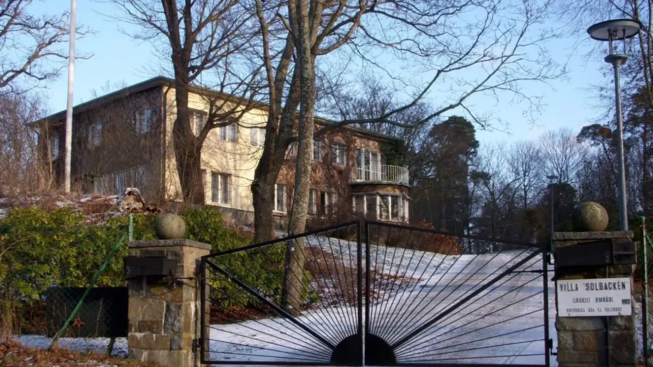 Här bor prins Carl Philip. Villa Solbacken, en vacker byggnad med en imponerande grind, omgiven av träd och snö.