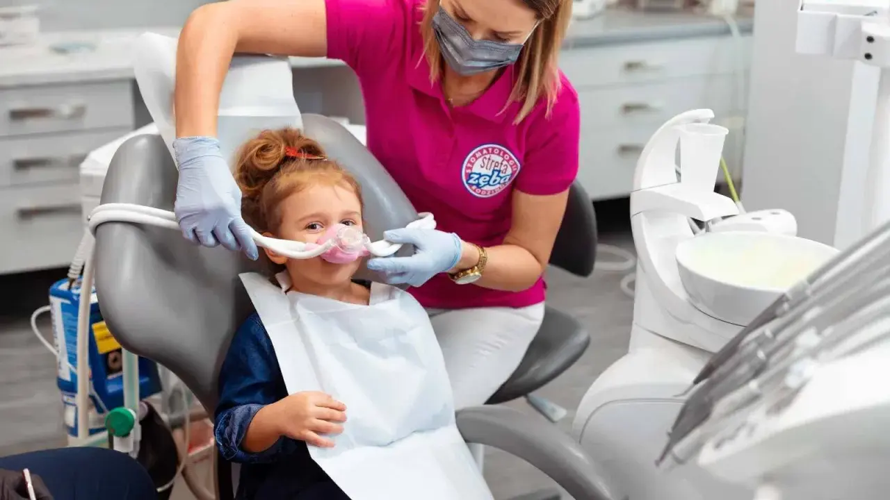 Dziecko w masce do sedacji wziewnej. Dentystka monitoruje stan pacjenta, minimalizując potencjalne skutki uboczne.