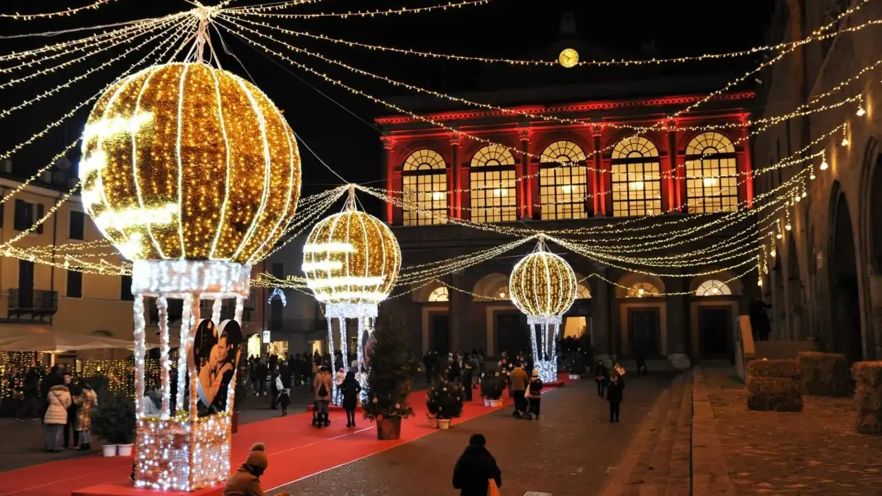 Luci scintillanti e palloni luminosi creano un'atmosfera magica per un week end a Rimini. Persone passeggiano su un tappeto rosso, ammirando le decorazioni natalizie.