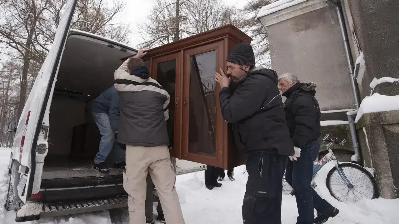 Mężczyźni wynoszą mebel z domu, by uniknąć eksmisji. Zimowa aura i śnieg nie powstrzymują przeprowadzki.