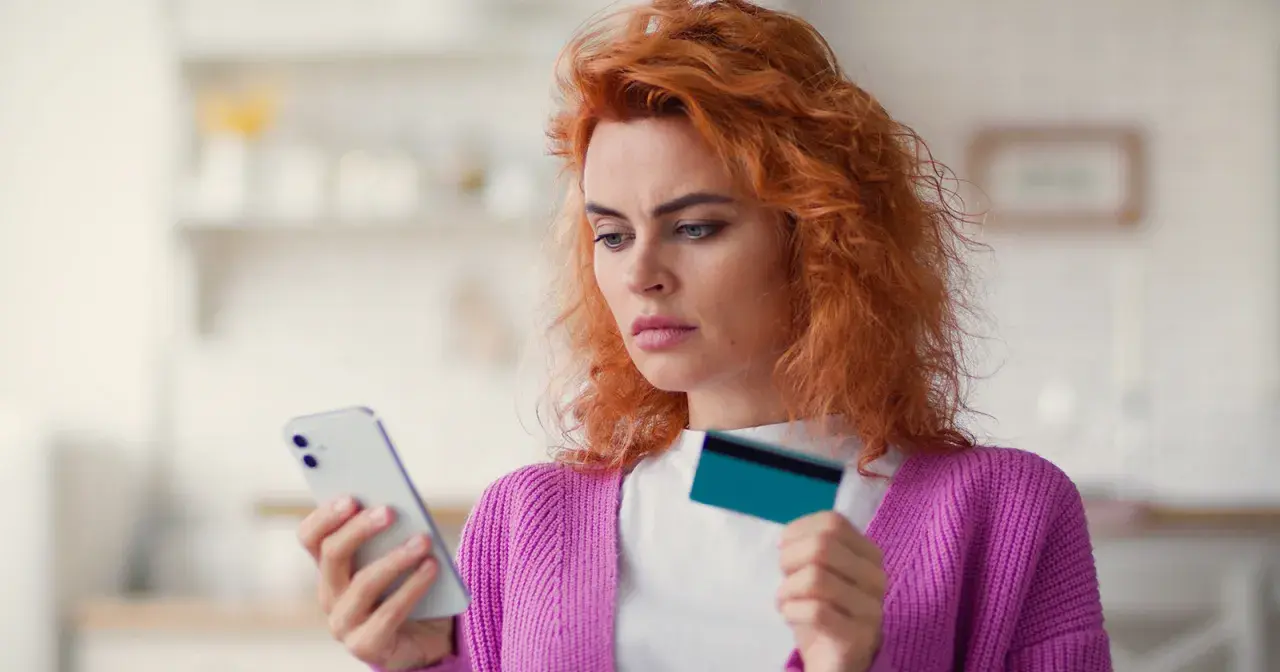 Zastanawia się, co to jest dip, przeglądając ofertę w telefonie z kartą w dłoni.