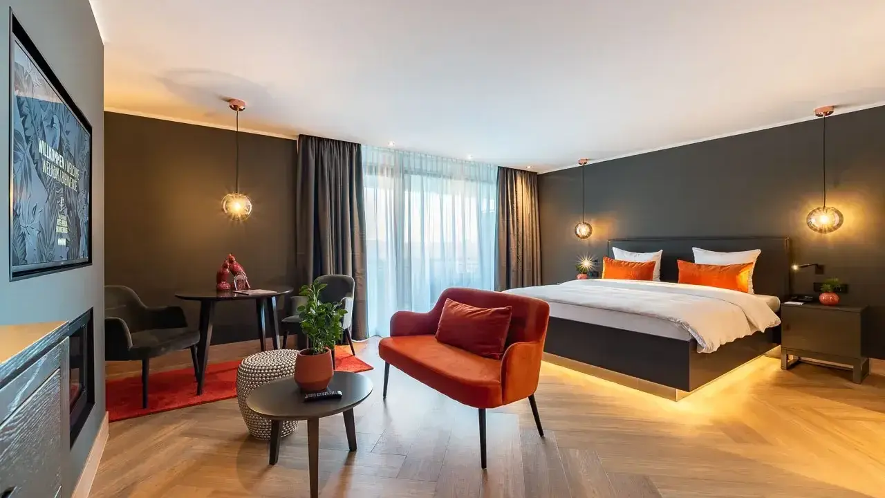 Modern Hotelzimmer mit großem Bett, orangefarbenem Sofa und Sitzbereich.