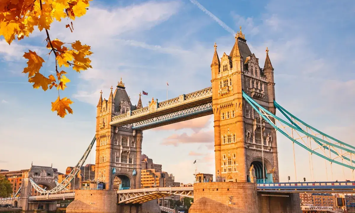 Tower Bridge w Londynie w jesiennym słońcu z liśćmi klonu na pierwszym planie.