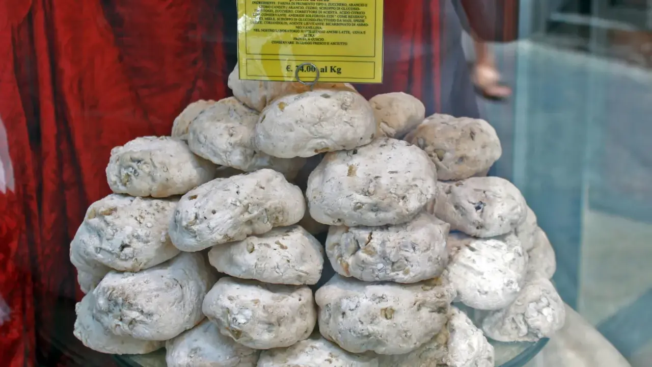 Dolce senese: cavallucci, biscotti rustici con noci e agrumi, impilati su un piatto di vetro.