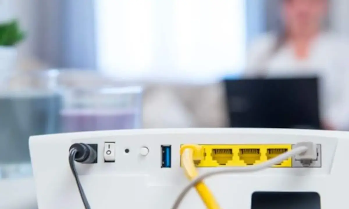 Router vom Strom trennen wie lange? Das Bild zeigt die Rückseite eines weißen Routers mit Netzteilanschluss, Schalter und LAN-Ports.