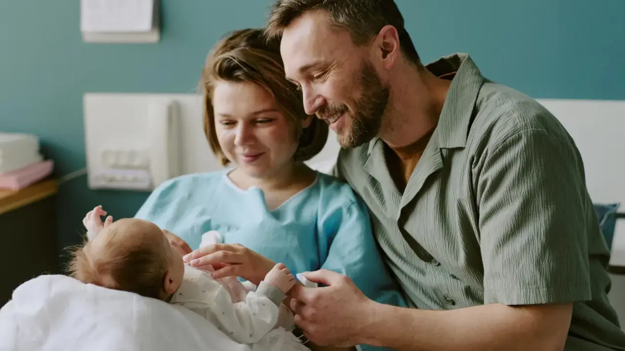 Szczęśliwi rodzice z noworodkiem w szpitalu. Dowiadują się o świadczenia po urodzeniu dziecka.