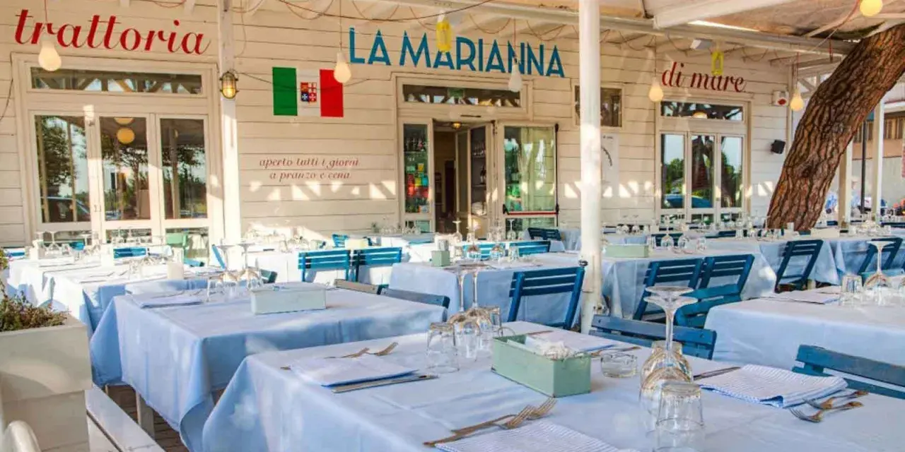 La Marianna Rimini, trattoria sul mare, con tavoli apparecchiati all'esterno sotto un grande albero.