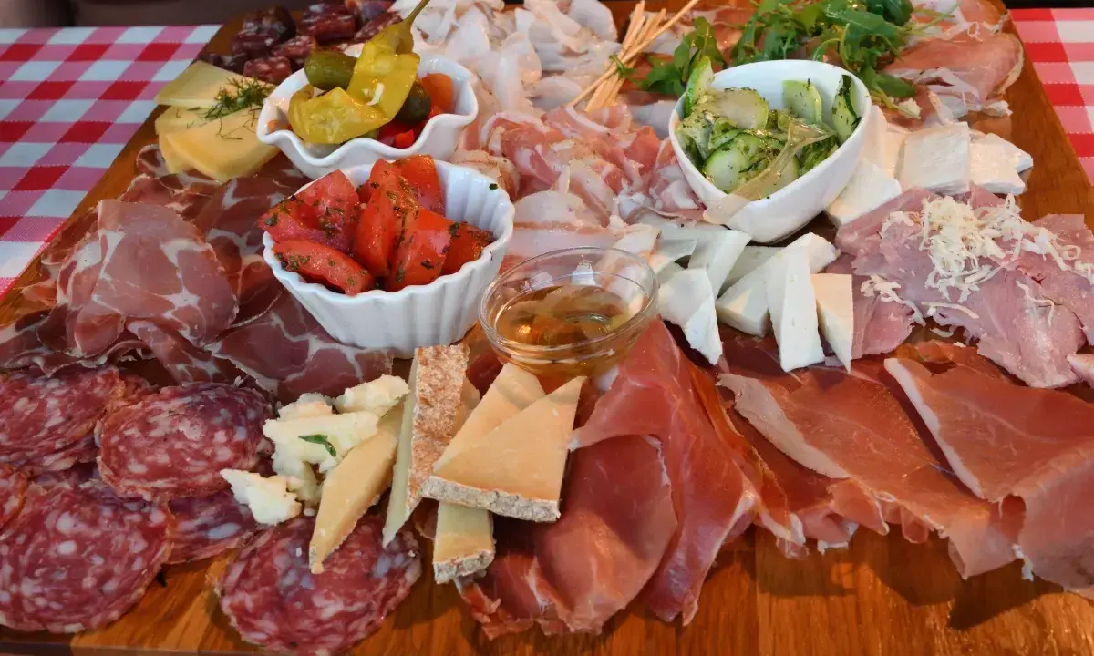 Tagliere ricco con salumi, formaggi, pomodori e sottaceti, un assaggio dei piatti tipici del Friuli Venezia Giulia.