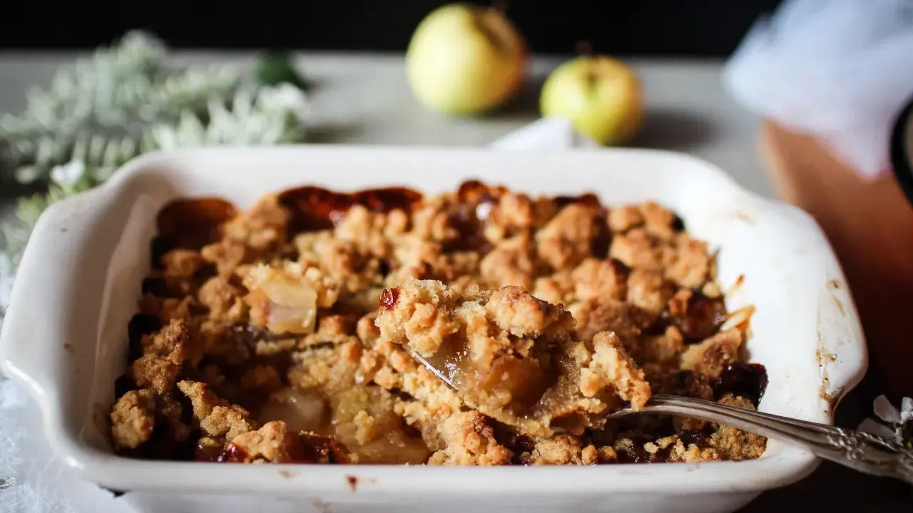 Une cuillère prélève une portion généreuse de ce vrai recette crumble aux pommes caramélisées, fondant et croustillant.