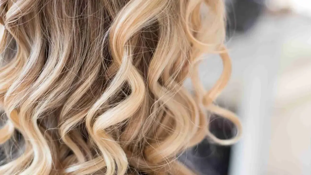 Piękne, falowane włosy z subtelnym balejażem blond, dodającym im blasku i głębi.