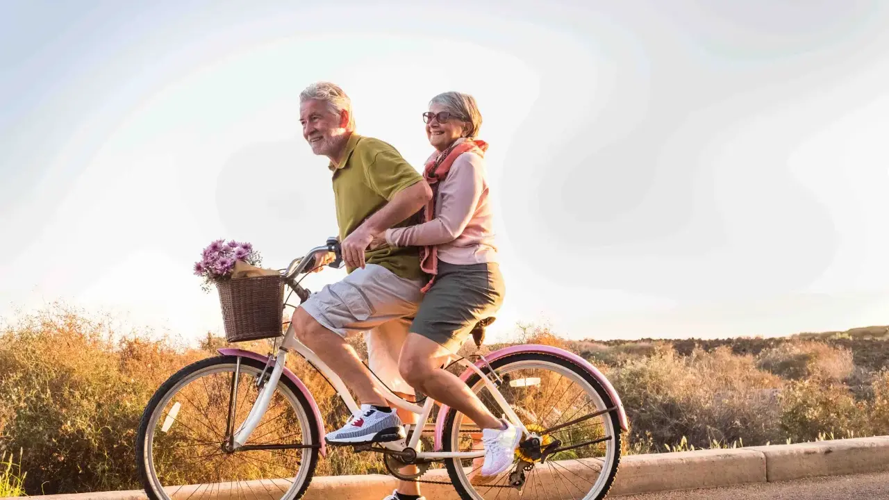 Pareja mayor disfruta de un paseo en bicicleta, celebrando la jubilación a los 61 años con la nueva reforma.